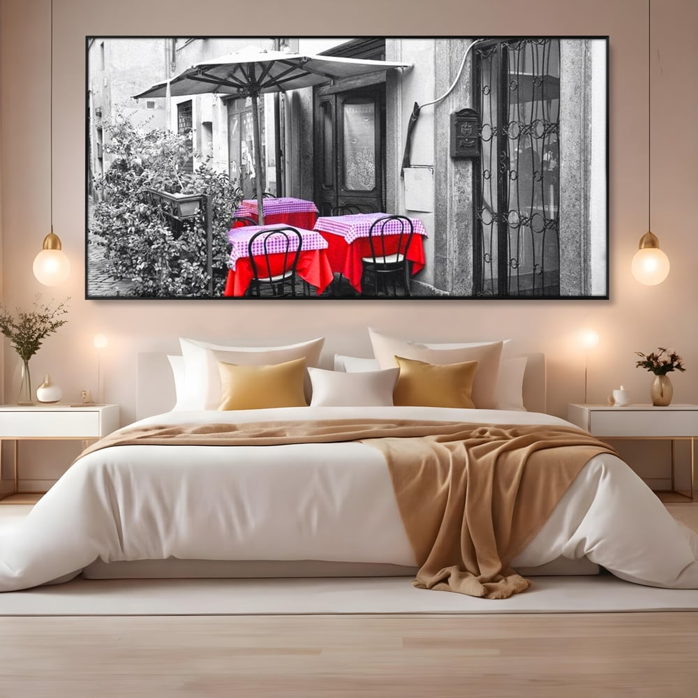Tablou canvas cu cafenea stradala vintage alb negru cu pete de rosu, in rama de aluminiu negru, pe perete intr-un dormitor